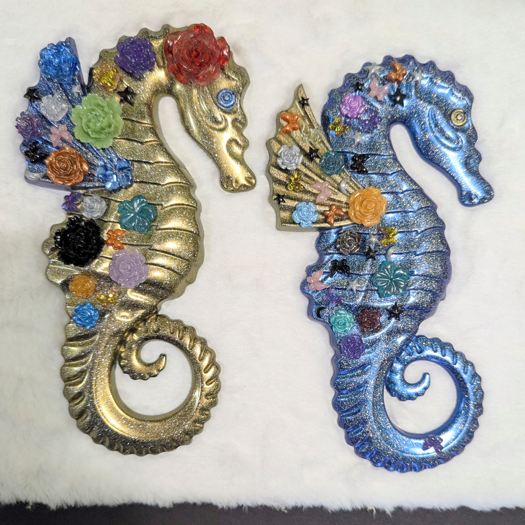 Handmade resin seahorse duo — gold with colorful flowers and iridescent blue with floral and star embellishments