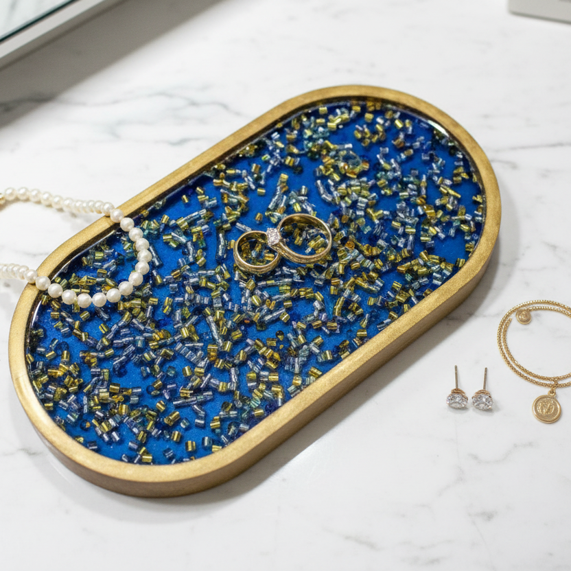 Royal blue resin tray with gold rings, pearl necklace and earrings on top